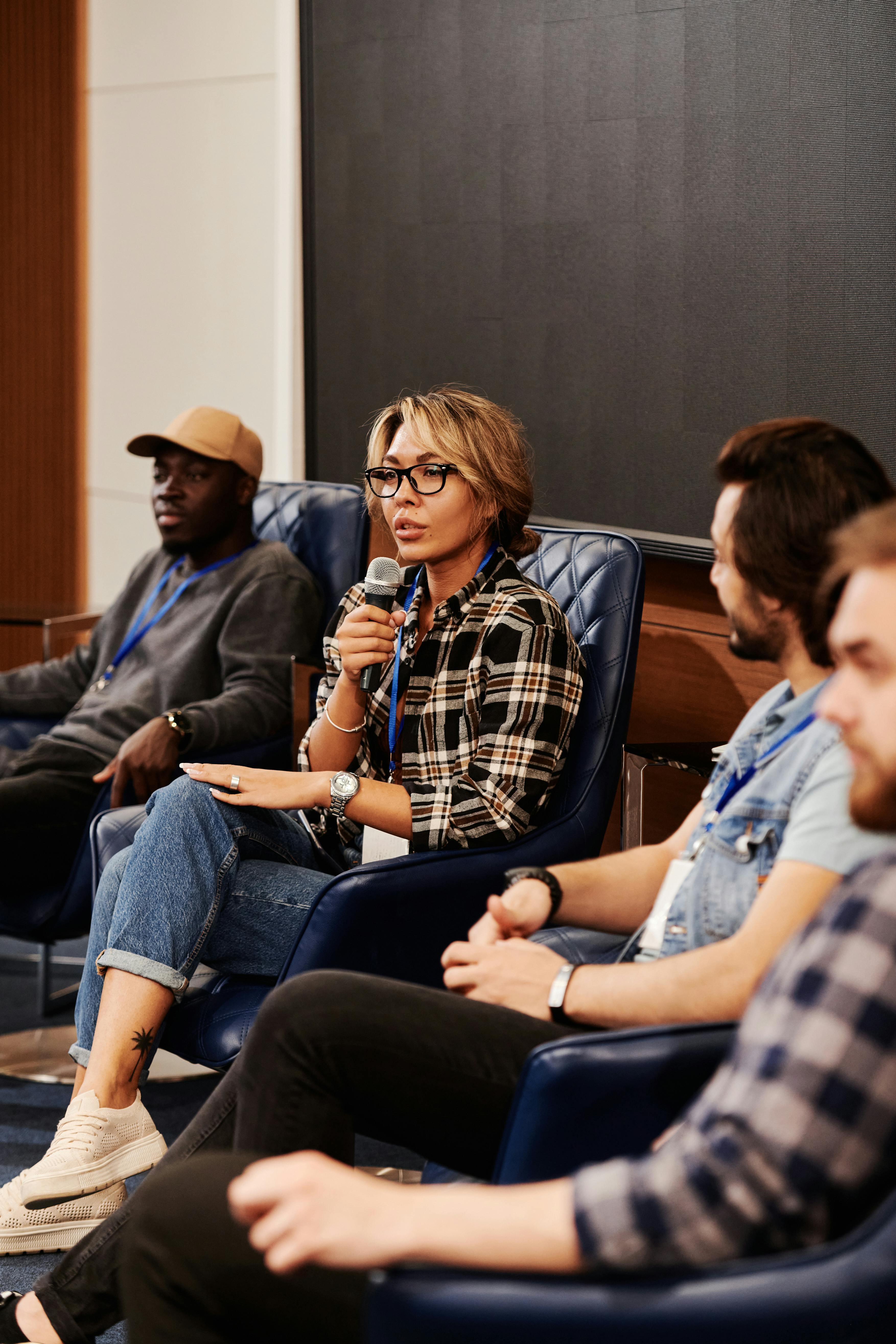 A diverse group of adults engaged in a panel discussion during a business seminar. Indoors setting.